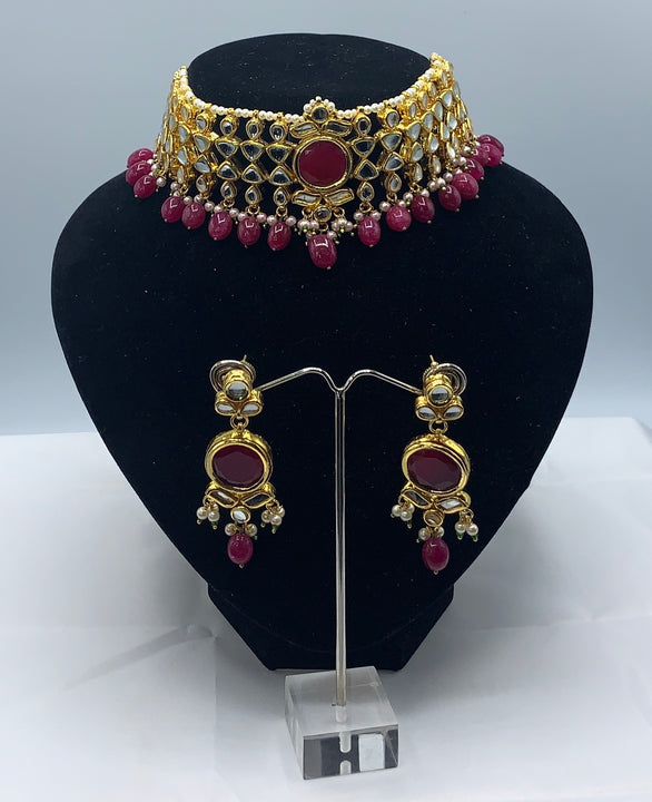 Choker style gold plated Kundan set with ruby coloured moti adorned with ruby colour stone and comes with matching earrings